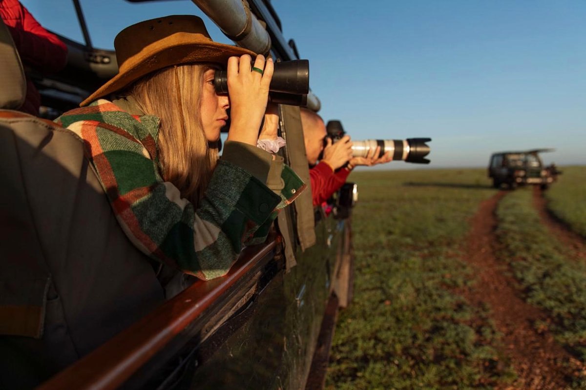 Des touristes dans un 4x4 découvert lors d'un safari au Kenya scrutent la savane avec des jumelles et un objectif télé — Guide complet pour préparer un safari au Kenya (Édition 2026)