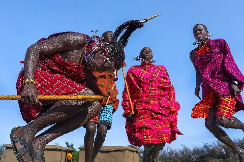 Maasai warriors in bright red shukas performing the traditional high-jump dance under a clear blue sky