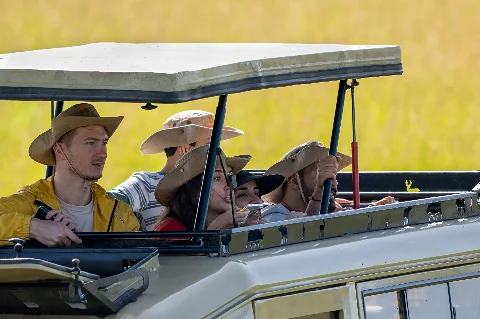 Tourists in an open-top safari vehicle wearing wide-brim hats, scanning golden plains on a 2-Day Amboseli National Park Safari